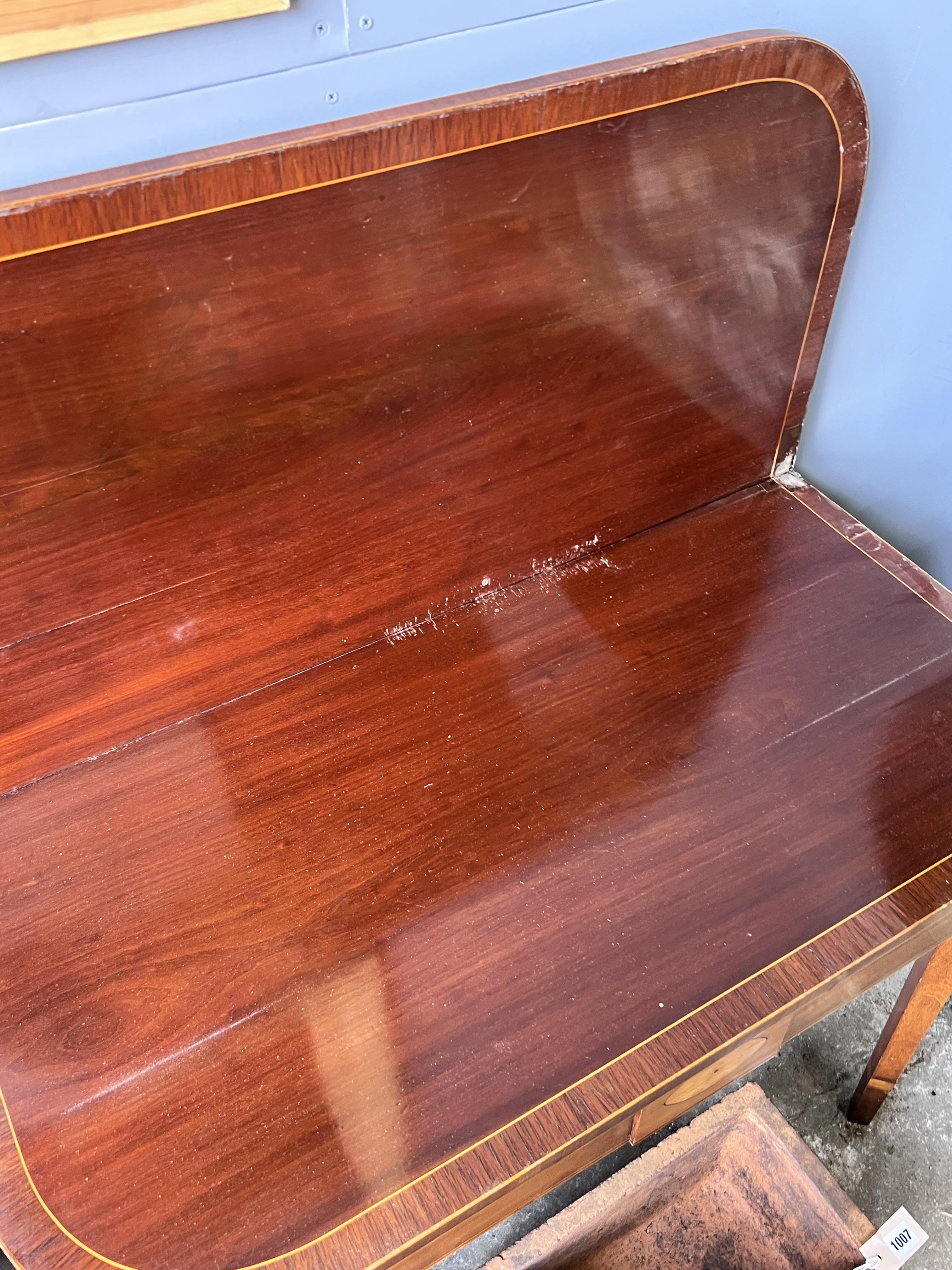 A George III rosewood banded inlaid mahogany tea table, width 92cm, depth 45cm, height 74cm (one leg in need of restoration)